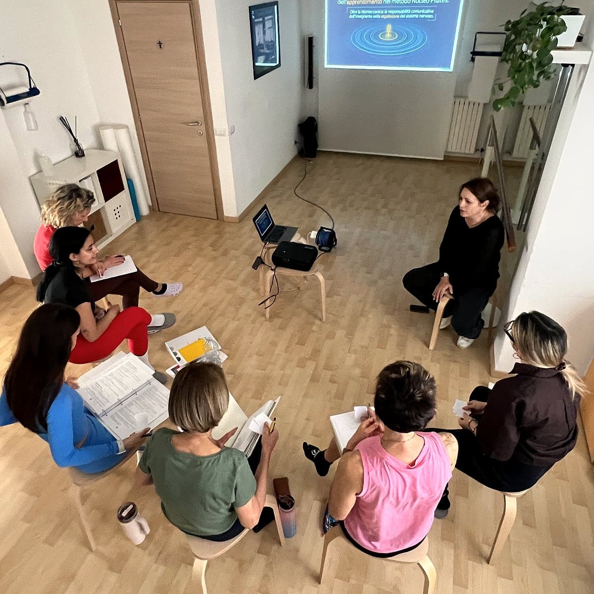 La classe segue una lezione teorica seduta in cerchio davanti allo schermo.